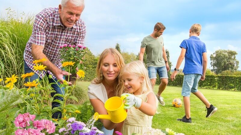 Familie im Garten beim Blumen Gießen und Spielen